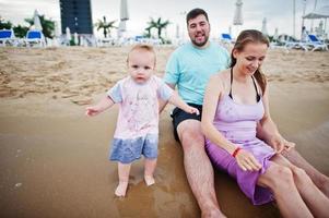 férias de verão. pais e pessoas atividade ao ar livre com crianças. boas férias em família. pai, mãe grávida, filha bebê na praia de areia do mar. foto