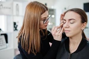 maquiadora trabalha em seu salão de beleza. mulher aplicando pelo mestre de maquiagem profissional. conceito de clube de beleza. foto