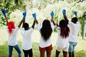 parte traseira do grupo feliz voluntários africanos de mãos dadas no parque. áfrica voluntariado, caridade, pessoas e conceito de ecologia. foto