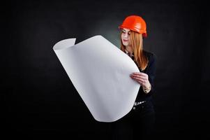 mulher engenheira em laranja proteger capacete com projeto de papel de construção. foto