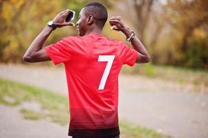 homem afro-americano em t-shirt de esporte de futebol vermelho com número 7 contra o parque outono. foto
