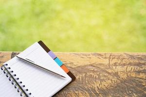 caderno em branco com caneta e lápis na mesa de madeira, conceito do negócio foto