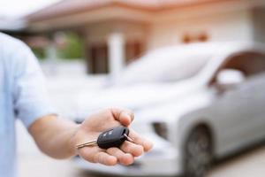 chave do carro, homem entregando dá a chave do carro para o outro homem no carro um fundo de casa. deixe espaço para escrever uma descrição do texto da mensagem. foto