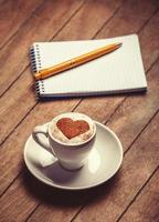 xícara de café com notebook em uma mesa de madeira.