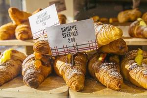 vários sabores de croissant ou como na itália seu chamado brioche em exposição em uma padaria em milão, itália com preço e sinal - albicocca significa geléia em italiano foto