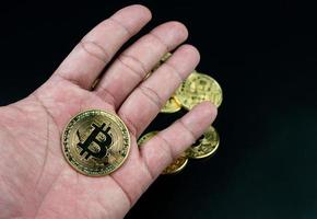 moeda bitcoin colocada na mão em um fundo preto foto