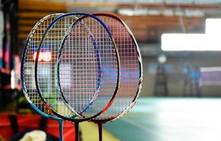 raquetes de badminton para badminton jogando na quadra de badminton indoor com sombreamento de luz neon no chão verde, fundo de badminton desfocado, copie o espaço. foto