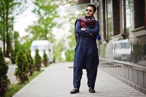 homem árabe muçulmano indiano paquistanês elegante em terno kurta dhoti e óculos de sol. foto