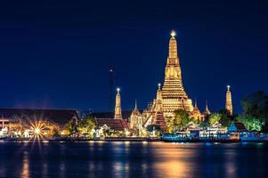 visão noturna do templo wat arun através do rio chao phraya em bangkok, tailândia. foto