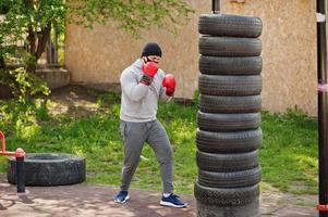 retrato esportivo homem boxer árabe em máscara facial médica preta boxe ao ar livre durante a quarentena de coronavírus. foto