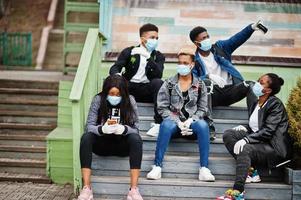 grupo de amigos adolescentes africanos no parque usando máscaras médicas protegem contra infecções e doenças quarentena de vírus coronavírus. foto