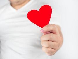 um homem de roupas brancas segurando coração de papel vermelho significa amor no mês do amor dia dos namorados foto