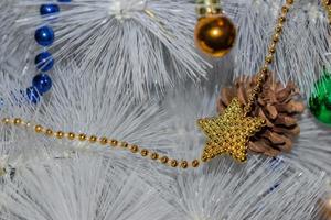 feriados, ano novo e conceito de celebração - árvore de natal branca. guirlanda dourada e azul, pinha, bolas verdes e douradas foto