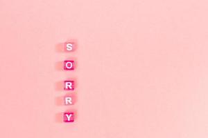 desculpe inscrição feita de contas de cubo colorido com letras. conceito de fundo rosa festivo com espaço de cópia foto