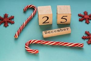calendário de blocos de madeira mostrando 25 de dezembro. feriado de Natal. cartão com bastões de doces e flocos de neve cintilantes. foto