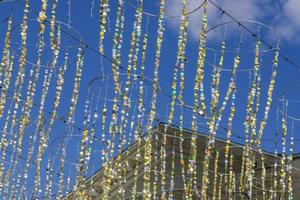 fitas de brilho festivo com círculos de ouro contra a fachada do edifício e o céu azul. guirlanda colorida para decoração de eventos da cidade foto