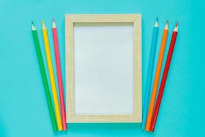 postura plana criativa com material escolar. mock up frame e lápis multicoloridos sobre fundo azul. de volta à escola. foto