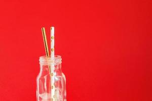 desperdício Zero. papel reciclável bebendo canudos de coquetel em garrafa de vidro vintage sobre fundo vermelho. foto