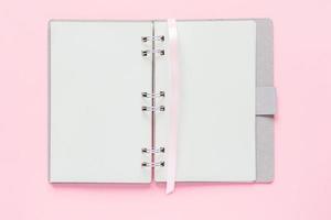 vista superior do caderno vazio aberto com capa de papel reciclado em fundo colorido rosa pastel foto