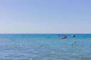 horison mar, turista em catamarãs e bóias de plástico marcando uma área restrita na água. foto