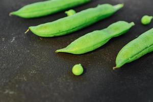 close-up de ervilhas verdes maduras frescas sobre fundo preto. alimentos orgânicos saudáveis foto