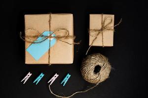 caixas de presente artesanais embrulhadas em papel craft com etiqueta de cartão de papel azul, corda e prendedores de roupa de madeira para decoração. foto