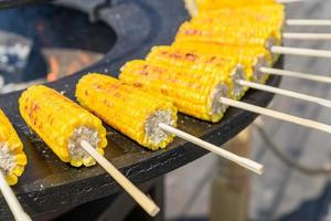 close-up de milho doce grelhado em varas. comida de rua foto