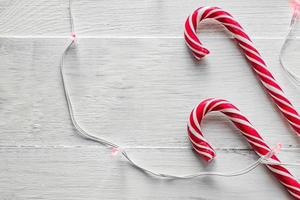 dois bastões de doces e guirlanda elétrica em fundo de madeira. doces tradicionais de natal. foto