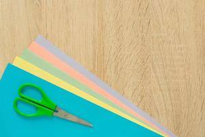 vista superior de papel multicolorido e tesoura na mesa de madeira. vista do topo. arranjo para trabalho criativo ou artesanato. foto