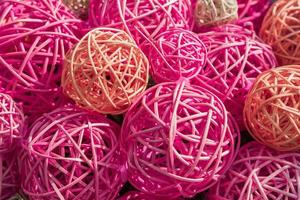 muitas bolas de ratã multicoloridas juntas. fundo colorido em tons de rosa foto