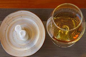 copo de vinho com conhaque ou conhaque ao lado do prato com toalhas de mão quentes molhadas em uma mesa. vista do topo foto