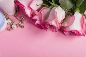 rosas desabrochando e creme para o rosto em fundo rosa pastel. moldura floral de skincare romântico. espaço de cópia foto