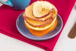 nutrição orgânica de alimentos saudáveis. maçã fatiada e seca, laranja e xícara de chá na toalha de mesa têxtil. foto