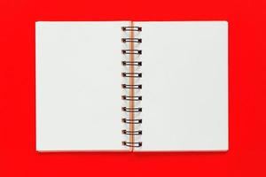 caderno espiral limpo para notas e mensagens sobre fundo vermelho. postura plana de negócios mínima foto