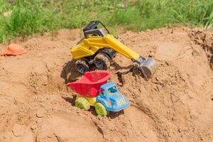 brinquedos de plástico em uma caixa de areia ao ar livre. caminhão e escavadeira para brincar na areia foto