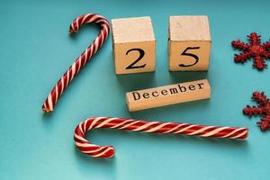 calendário de blocos de madeira mostrando 25 de dezembro. feriado de Natal. cartão com bastões de doces e flocos de neve cintilantes. foto