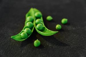 close-up de ervilhas verdes maduras frescas sobre fundo preto. alimentos orgânicos saudáveis foto