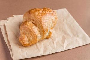 close-up de croissant francês recém-assado em papel ofício no café da manhã.