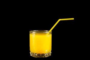 suco de laranja fresco e saudável em um copo com canudo de coquetel em fundo preto foto