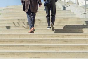 duas pessoas em roupas casuais de negócios andando no andar de cima ao ar livre. fundo urbano foto