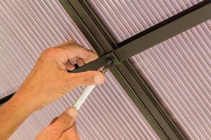 mãos masculinas segurando o telhado de fixação de chave de soquete feito de policarbonato foto