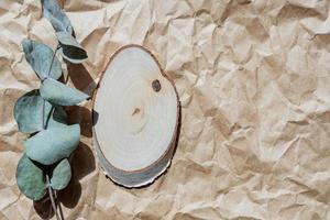 pódio de madeira redondo vazio para apresentação do produto, ramo de eucalipto em fundo de papel artesanal. fundo de materiais naturais para close-up de publicidade cosmética, vista superior foto