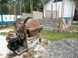 uma betoneira instalada em um canteiro de obras ao lado de uma pilha de areia e cascalho. foto