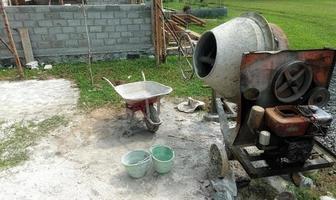 uma betoneira instalada em um canteiro de obras ao lado de uma pilha de areia e cascalho. foto