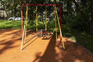 bebê balança em um playground em um dia ensolarado de verão no parque da cidade foto