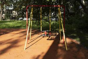 bebê balança em um playground em um dia ensolarado de verão no parque da cidade foto