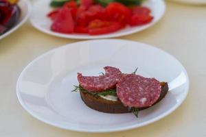 sanduíche com linguiça defumada em um prato branco foto