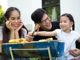 família mãe pai filho menina pessoas jovem adulto feliz piquenique Comida grelha churrasco comer carne almoço jantar ao ar livre jardim parque Diversão Prazer sorrir estilo de vida vocação juntos foto