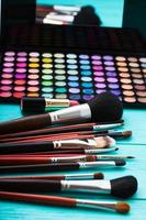 ferramentas de maquiagem. produtos de maquiagem. batom, sombra para os olhos, brushes.cosmetics em fundo azul de madeira.foco seletivo foto