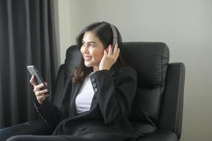 jovem mulher de negócios relaxante usando smartphone e ouvindo música no escritório moderno. foto